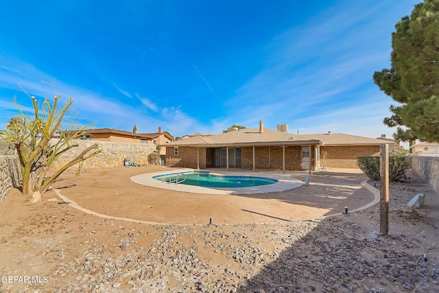 back of property with a fenced in pool and a patio area