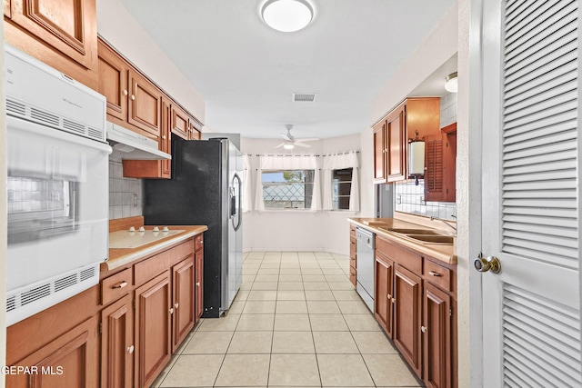 kitchen featuring sink, decorative backsplash, light tile patterned floors, ceiling fan, and white appliances