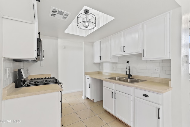 kitchen featuring appliances with stainless steel finishes, sink, white cabinets, backsplash, and light tile patterned floors