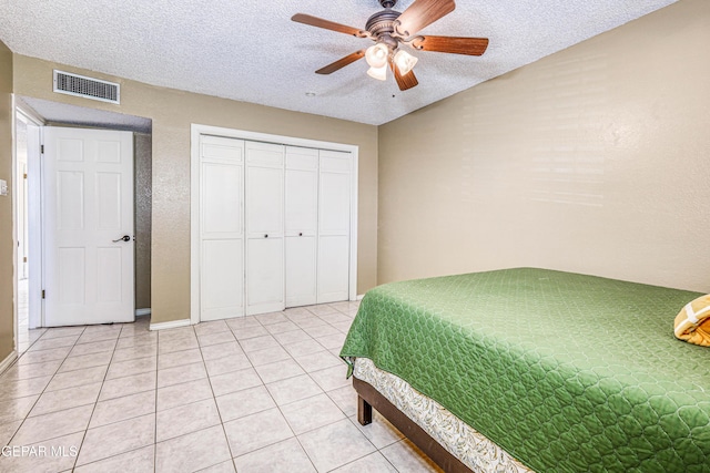 tiled bedroom with ceiling fan, a closet, vaulted ceiling, and a textured ceiling