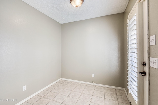 empty room with light tile patterned flooring and a textured ceiling