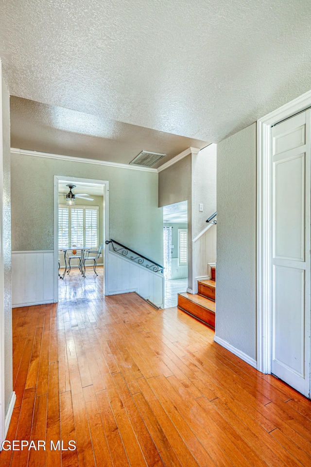 unfurnished room with crown molding, hardwood / wood-style floors, ceiling fan, and a textured ceiling