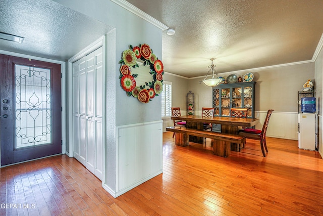 entrance foyer with hardwood / wood-style flooring, ornamental molding, and a textured ceiling