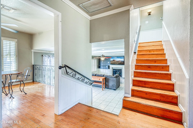 staircase featuring crown molding, ceiling fan, and wood-type flooring