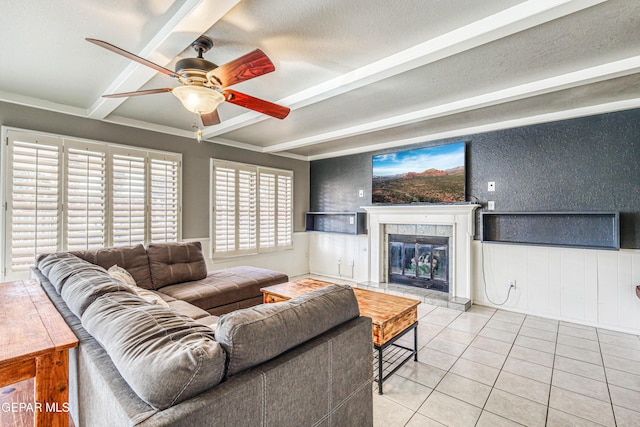 tiled living room with ceiling fan, beam ceiling, a tile fireplace, and a textured ceiling