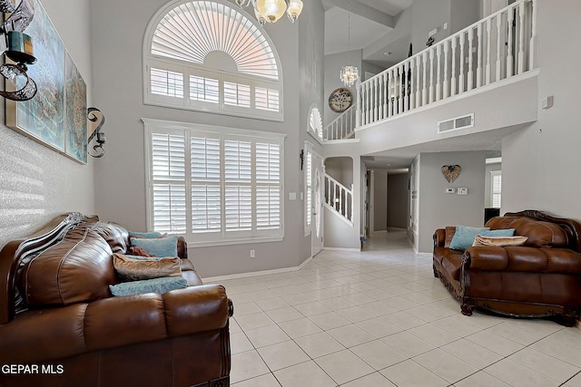 tiled living room with an inviting chandelier and a high ceiling