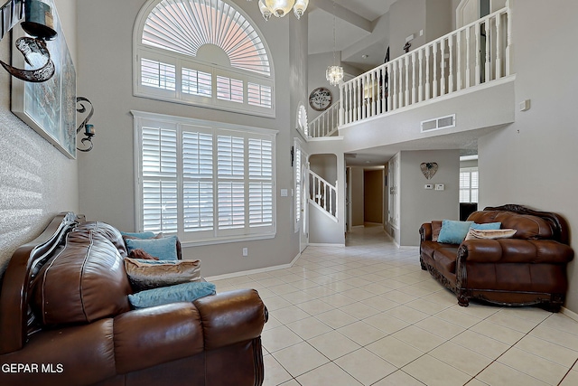 tiled living room featuring a wealth of natural light, a chandelier, and a high ceiling