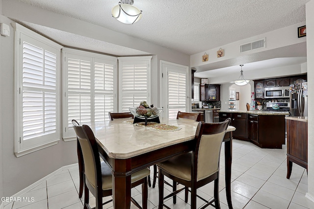 tiled dining area with a textured ceiling