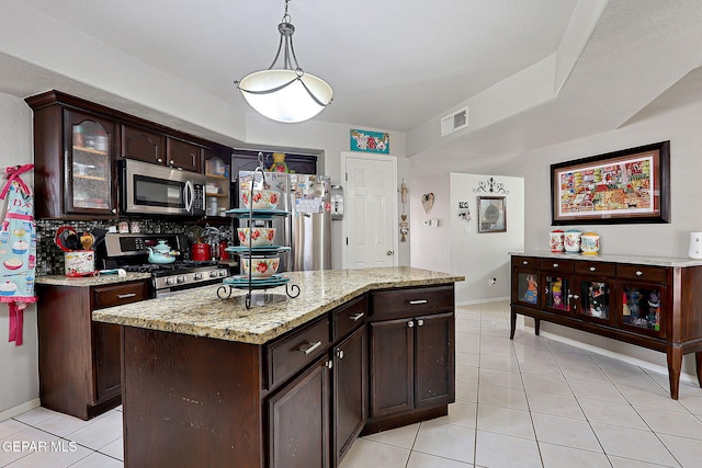 kitchen with light tile patterned flooring, dark brown cabinets, hanging light fixtures, appliances with stainless steel finishes, and a kitchen island