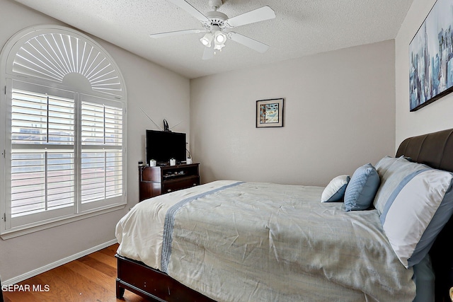 bedroom featuring hardwood / wood-style flooring, ceiling fan, and a textured ceiling