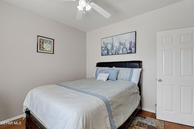 bedroom with dark hardwood / wood-style flooring, ceiling fan, and a textured ceiling