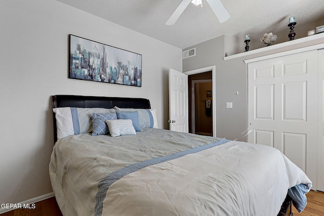 bedroom with hardwood / wood-style flooring, a textured ceiling, and ceiling fan