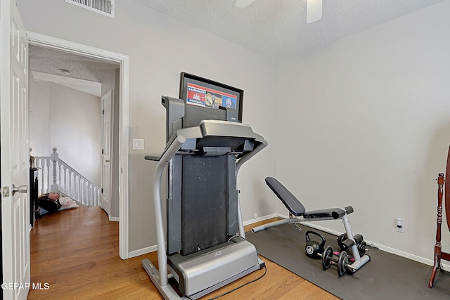 workout area featuring wood-type flooring and a textured ceiling