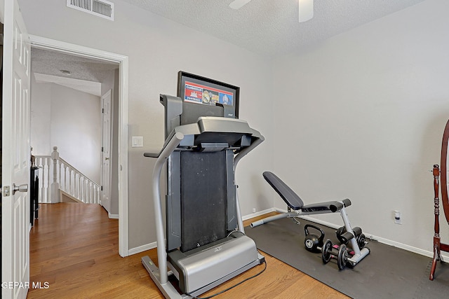 workout area with hardwood / wood-style flooring, ceiling fan, and a textured ceiling