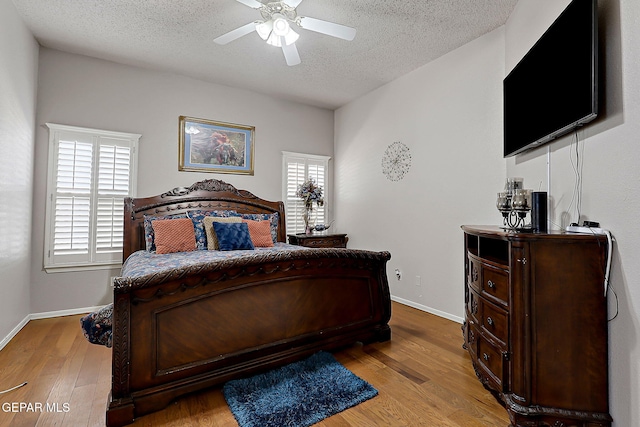 bedroom featuring ceiling fan, light hardwood / wood-style flooring, and a textured ceiling