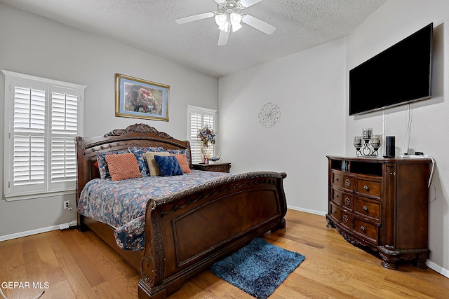 bedroom with ceiling fan, light hardwood / wood-style floors, and a textured ceiling