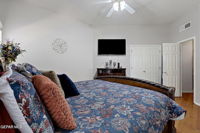 bedroom with ceiling fan, hardwood / wood-style floors, and a textured ceiling