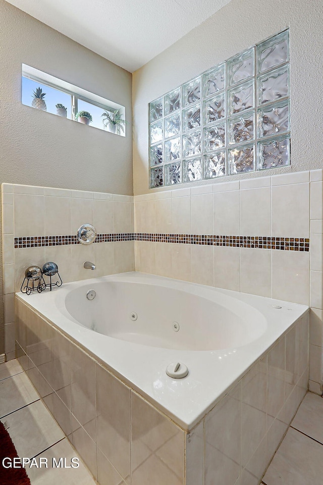 bathroom featuring a relaxing tiled tub, tile patterned floors, and a textured ceiling