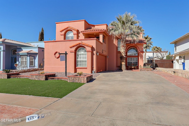 mediterranean / spanish home with a garage and a front lawn