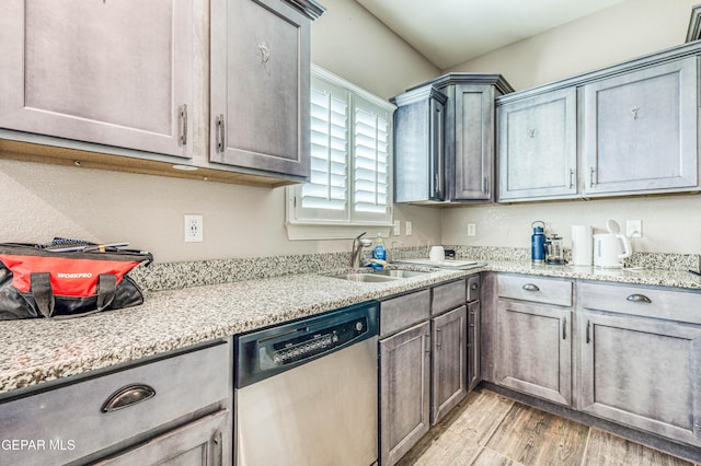 kitchen with sink, light stone countertops, dishwasher, and light wood-type flooring