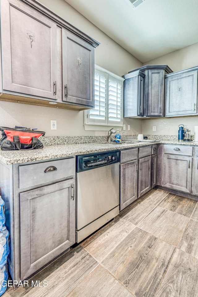 kitchen featuring dishwasher, light stone counters, and light hardwood / wood-style floors