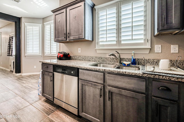 kitchen featuring light stone counters, dark brown cabinetry, dishwasher, and sink