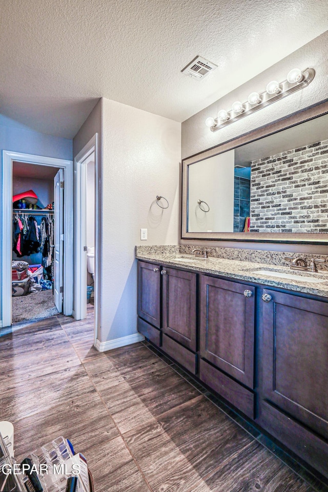 bathroom with vanity, hardwood / wood-style floors, a textured ceiling, and toilet