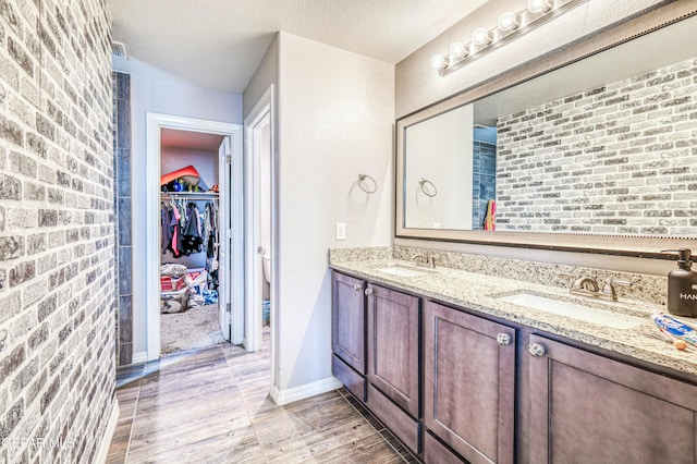 bathroom featuring brick wall, vanity, hardwood / wood-style floors, and a textured ceiling