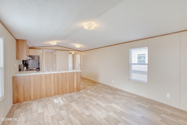 kitchen featuring lofted ceiling, black refrigerator, light brown cabinetry, kitchen peninsula, and light wood-type flooring