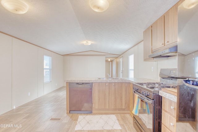 kitchen with appliances with stainless steel finishes, lofted ceiling, kitchen peninsula, light brown cabinets, and a textured ceiling