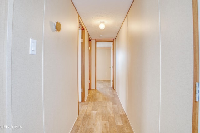 hall with light hardwood / wood-style floors and a textured ceiling