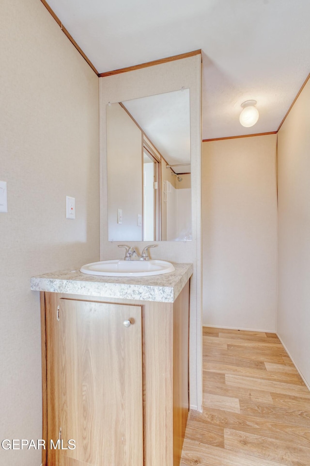 bathroom with hardwood / wood-style flooring, crown molding, and vanity