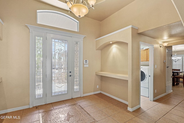 entrance foyer featuring washer / clothes dryer, light tile patterned floors, and a notable chandelier