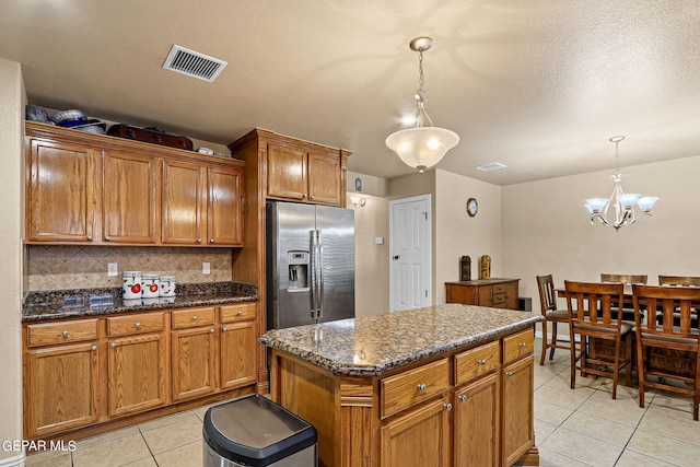 kitchen with light tile patterned flooring, tasteful backsplash, a center island, stainless steel fridge with ice dispenser, and hanging light fixtures