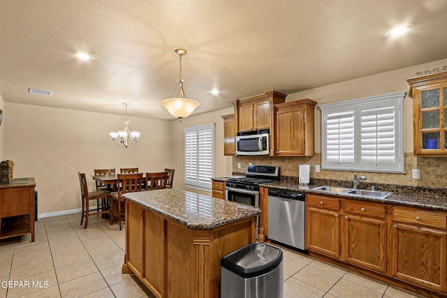 kitchen featuring sink, a center island, hanging light fixtures, appliances with stainless steel finishes, and backsplash