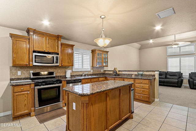 kitchen with appliances with stainless steel finishes, a center island, pendant lighting, and light colored carpet