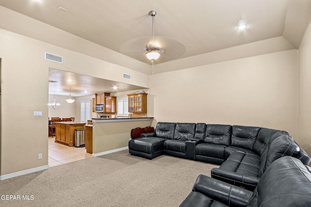 living room with light carpet, ceiling fan with notable chandelier, and vaulted ceiling