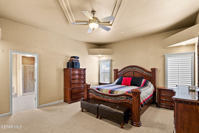 bedroom with ceiling fan, ensuite bath, light colored carpet, and a textured ceiling