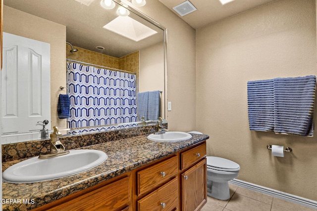 bathroom featuring a skylight, a shower with shower curtain, vanity, tile patterned floors, and toilet