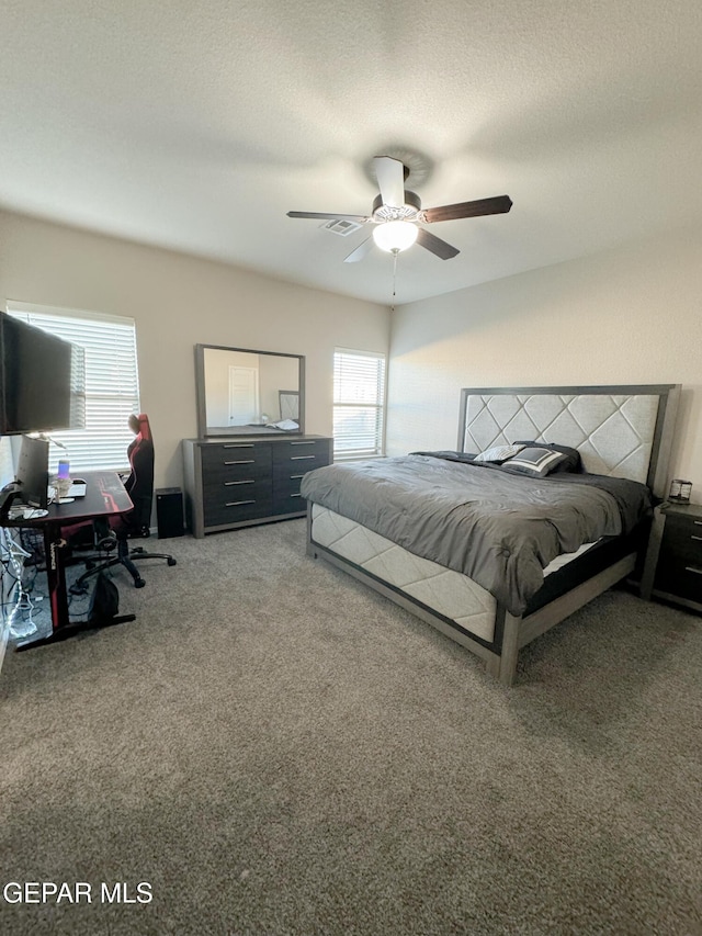 carpeted bedroom with ceiling fan and a textured ceiling