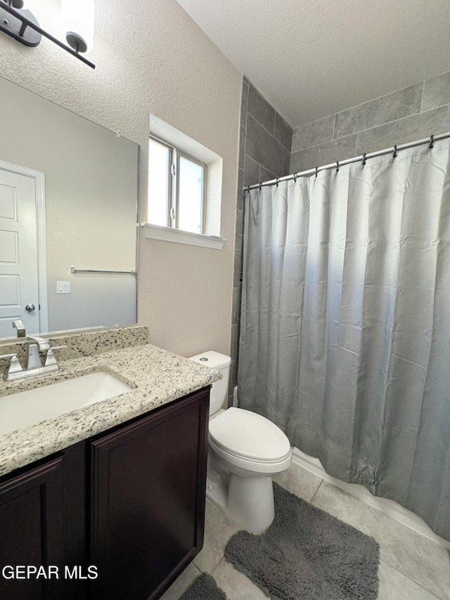 bathroom featuring vanity, toilet, tile patterned flooring, and a textured ceiling