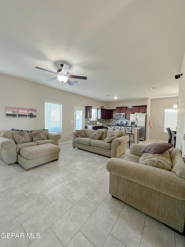 living room featuring light tile patterned flooring, ceiling fan, and a textured ceiling