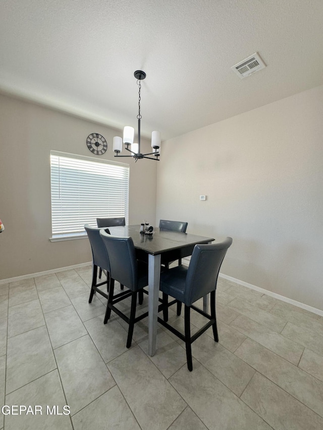 dining space with light tile patterned floors, a textured ceiling, and a notable chandelier