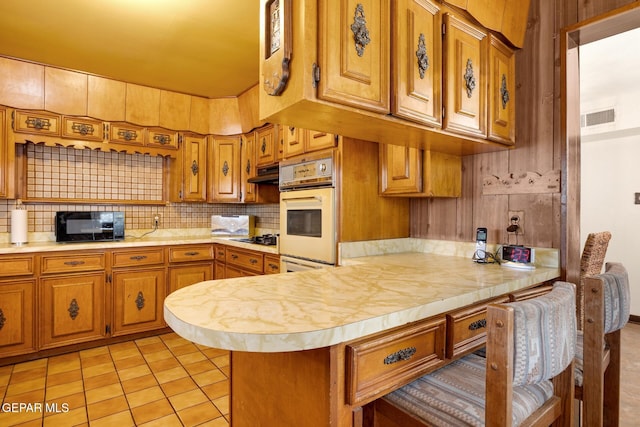 5047 Conley Rd, El Paso, TX 79932 - kitchen featuring backsplash, kitchen peninsula, light tile patterned floors, and black appliances
