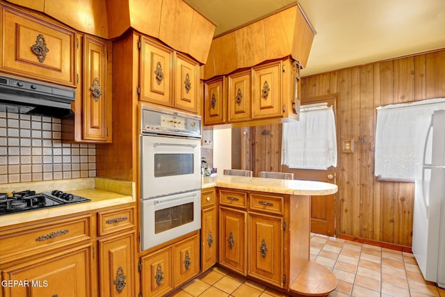 5047 Conley Rd, El Paso, TX 79932 - kitchen featuring wooden walls, decorative backsplash, white appliances, and kitchen peninsula