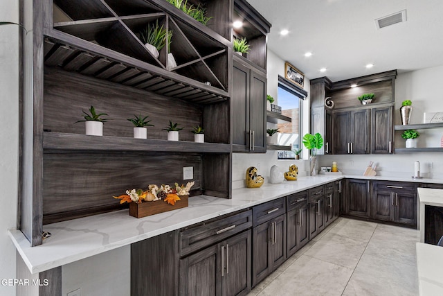 kitchen with tasteful backsplash, light stone countertops, and dark brown cabinets