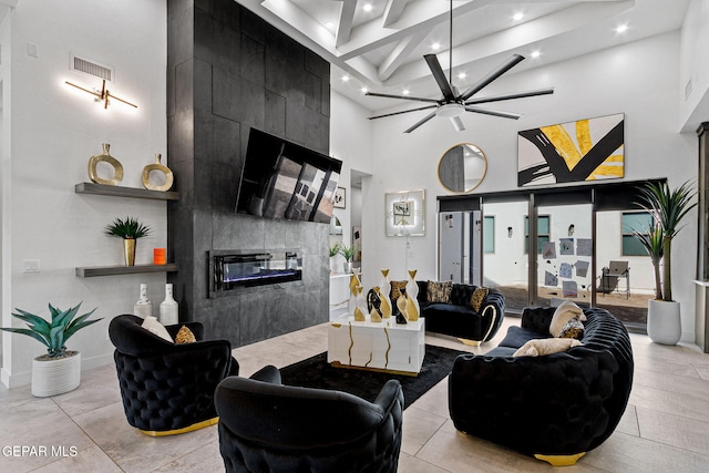 living room with a tiled fireplace and a high ceiling