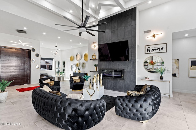 living room featuring ceiling fan, a towering ceiling, light tile patterned floors, and a fireplace