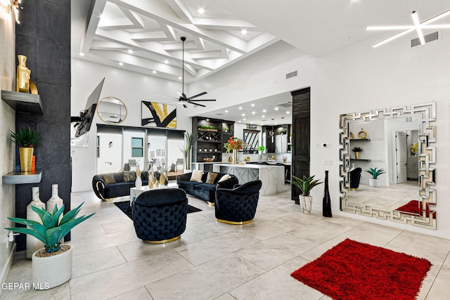 living room with a high ceiling, coffered ceiling, ceiling fan, and beamed ceiling