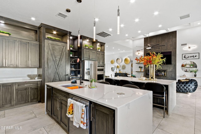 kitchen with stainless steel appliances, pendant lighting, light stone counters, and a spacious island